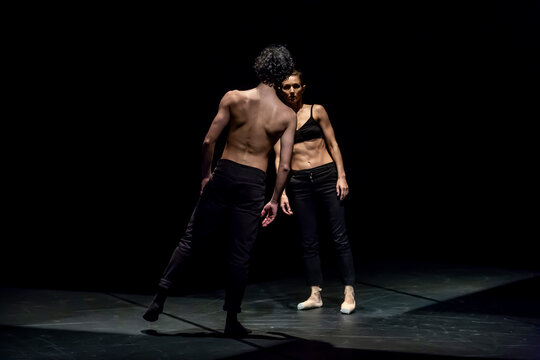 Male and femal dancer performing contemporary ballet on black stage