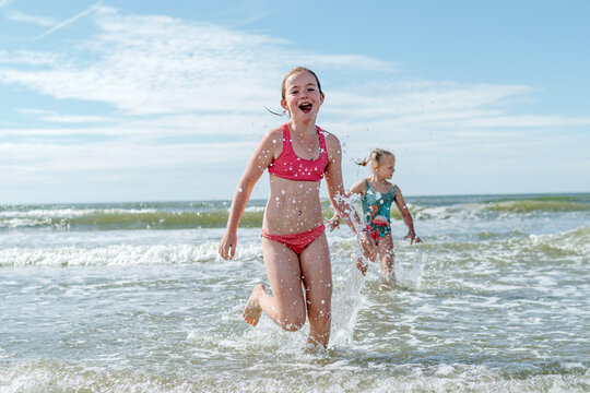 Girls running in water at beach on sunny day