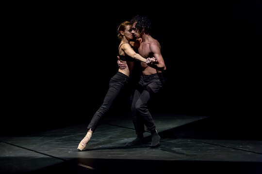 Male and femal dancer performing contemporary ballet on black stage