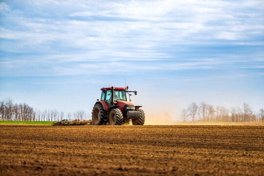 Farmer in tractor plowing field in spring