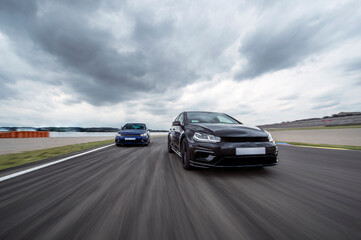 Cloudy sky over two sports cars racing on asphalt track