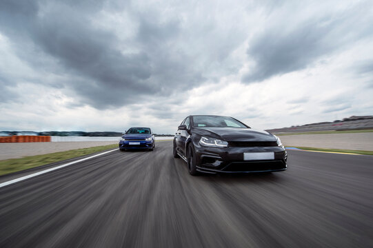 Cloudy sky over two sports cars racing on asphalt track