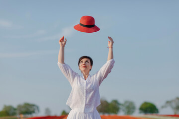 Portrait of woman throwing red hat into the air