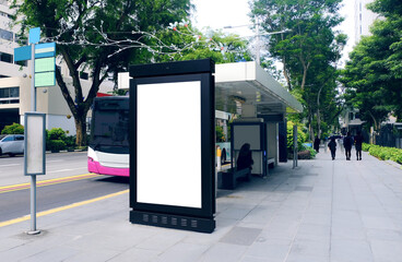 Blank advertising poster banner mockup at bus stop shelter by main road; out-of-home OOH vertical billboard media display space. Perspective angle.