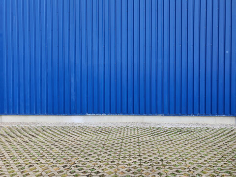 Paved terrain in front of blue corrugated iron wall