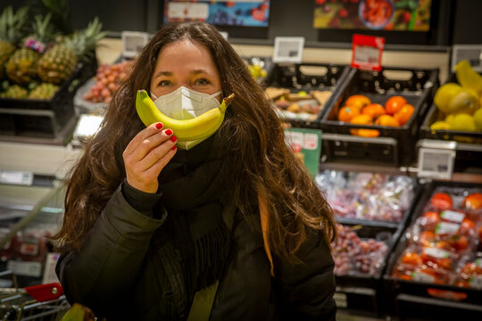 Mature Woman In Protective Face Mask Showing Banana While Shopping In Supermarket