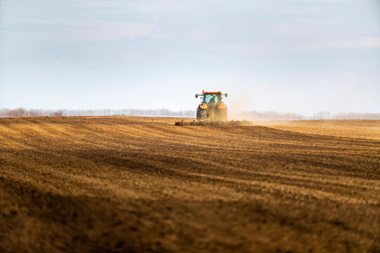 Farmer in tractor plowing field in spring