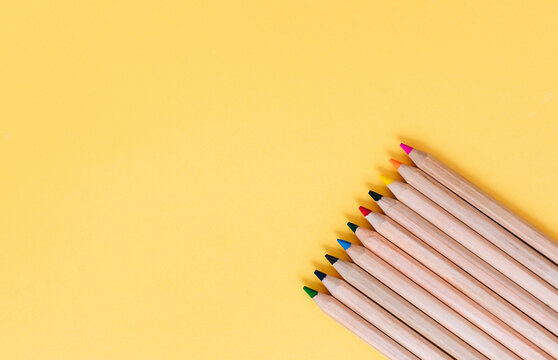 Colored pencils arranged on yellow background