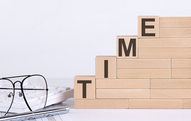 wooden cubes with letters TIME on the white table with keyboard and glasses