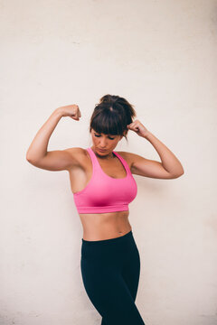 Fit woman flexing muscles while standing against wall