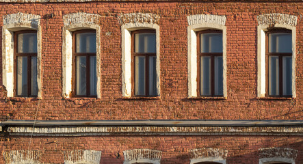 Obraz premium Brick wall of an old 19th century building with large windows. Wall of an old red brick building with five windows