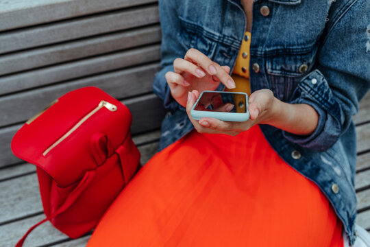 Young woman using smartphone sitting on bench