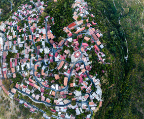 Aerial view above a rural hilly village with red brown roofs