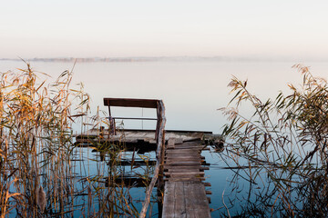 Drewniany pomost nad jeziorem, mglisty poranek nad jeziorem z pomostem, ławeczka nad jeziorem,...