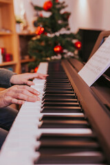 Close-up of girl hands on the piano, woman playing the piano. Christmas lights and music, concert, family time, holidays concept. Merry Christmas, happy new year.