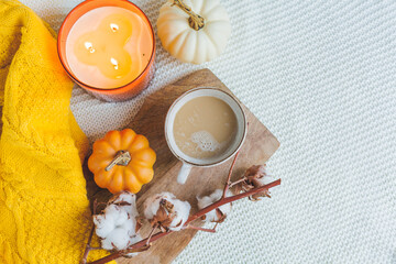 Fototapeta na wymiar Autumn mood. A cup of hot cappuccino, pumpkins, knitted yellow plaid on a wooden stand. A branch of cotton. copy space.