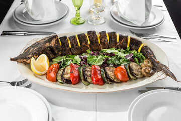 grilled Whole sturgeon Fish with lemon and grilled vegetables on plate
