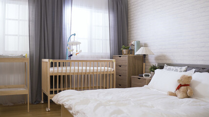 panoramic view of a contemporary bright organized bedroom equipped with a baby bed and a diaper change.