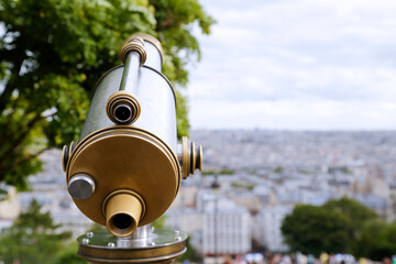 In the foreground a coin operated telescope in the background a view of the city of Paris, France