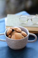 Bowl of cinnamon cookies, hardcover books and reaing glasses. Selective focus.
