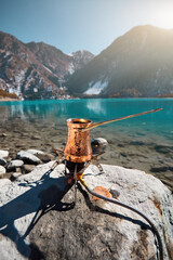 Copper Cezve for coffee in autumn lake camping in the mountains.