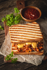 Close up view of tasty sloppy joe sandwich with ground meat, sauce and cheese on wooden background