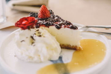 Una porcion de cheesecake con frutos rojos y nata