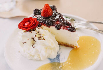 Una porcion de cheesecake con frutos rojos y nata