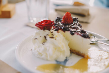 Una porcion de cheesecake con frutos rojos y nata