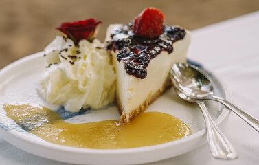 Una porcion de cheesecake con frutos rojos y nata