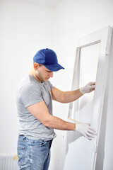 Young adult man painting and fixing on a DIY budget renovation of his new home apartment.