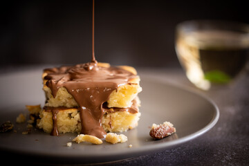 Melted chocolate pouring on cake with nuts	