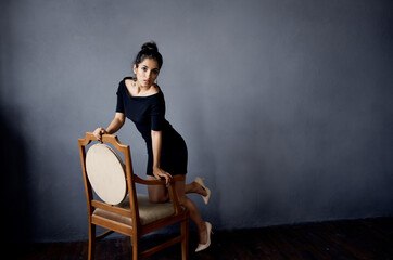 Obraz na płótnie Canvas pretty woman in a black dress near the chair luxury fashion lifestyle studio