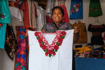 Mexican smiling at camera, mother working in regional clothing business