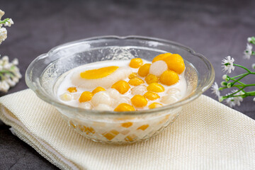 Pumpkin (white and yellow) rice dumpling in coconut milk (Bua Loy) in transparency bowl on wooden table. Delicious Thai dessert.