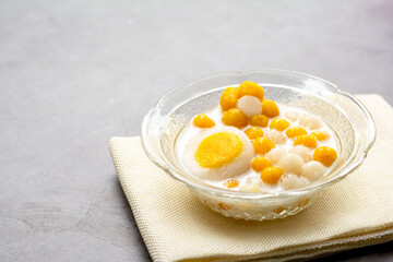 Pumpkin (white and yellow) rice dumpling in coconut milk (Bua Loy) in transparency bowl on wooden table. Delicious Thai dessert.