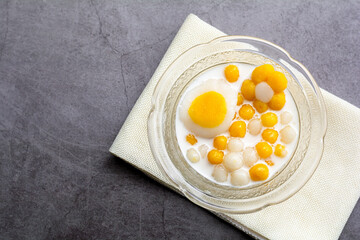 Pumpkin (white and yellow) rice dumpling in coconut milk (Bua Loy) in transparency bowl on wooden table. Delicious Thai dessert.