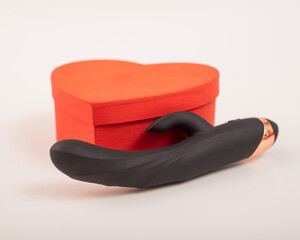 Black dildo and heart-shaped box on a white background