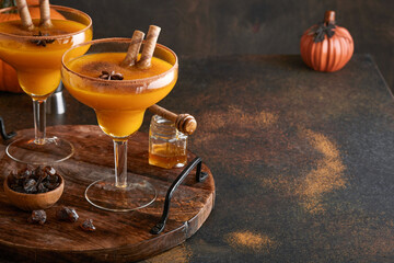Pumpkin cocktail with cinnamon, orange juice and cocoa in glass mugs. Pumpkin autumn drink for Halloween or Thanksgiving.