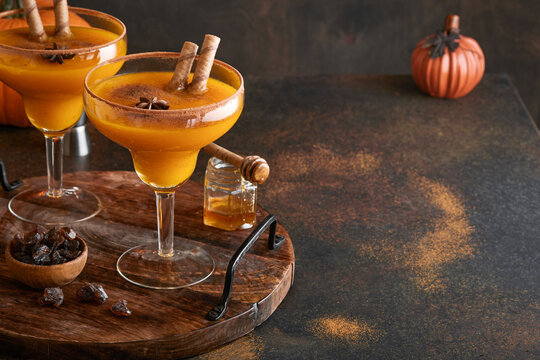 Pumpkin cocktail with cinnamon, orange juice and cocoa in glass mugs. Pumpkin autumn drink for Halloween or Thanksgiving.