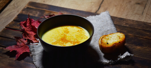 Pumpkin soup puree in a brown plate on a wooden table