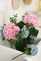 Vase with beautiful hortensia flowers in kitchen sink