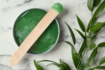 Spatula with wax and leaves on white marble table, flat lay - obrazy, fototapety, plakaty