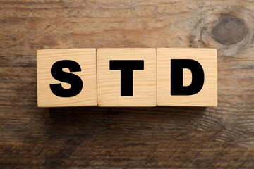 Abbreviation STD made with cubes on wooden table, flat lay