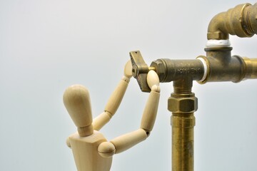 Muñeco de madera manipulando una llave de corte de una instalación de fontanería - obrazy, fototapety, plakaty