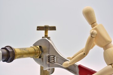 Muñeco de madera con una llave ajustable, apretando una tuerca de fontanería