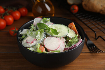 Bowl of delicious vegetable salad dressed with mayonnaise on wooden table, closeup