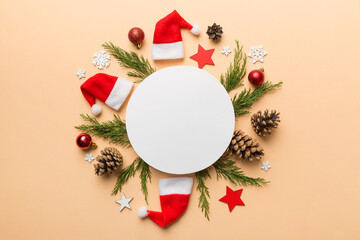 Flat lay Christmas composition. Round Paper blank, pine tree branches, christmas decorations on Colored background. Top view, copy space for text