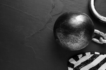 Prisoner ball with chain and jail cap on black table, flat lay. Space for text