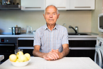 Portrait of an elderly lonely man at home in kitchen